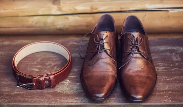 Brown leather shoes and belt on wooden floor