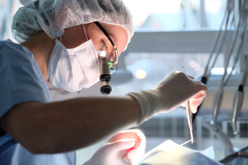 Female dentist in surgical uniform at the clinic in the treatment of a patient