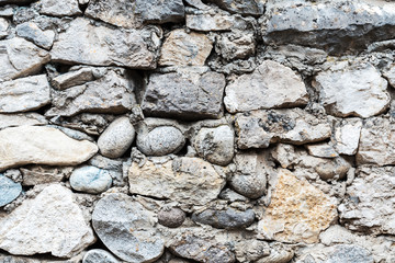 Background of grey and brown stonework wall with different forms stones and rough texture