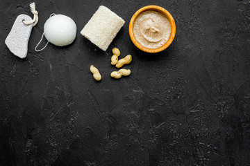 Obraz na płótnie Canvas organic scrub with peanut for homemade spa on black background top view mockup