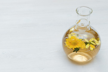 Chrysanthemum daisy flower essential oil tincture bottle on the white wooden table background with copy space. Herbal medicine.