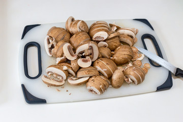 A pile of sliced chestnut mushrroms (Agaricus bisporus) on a white chopping board