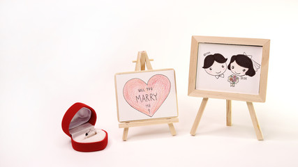 Surprise With Ring, Lovely Groom and Bride and Big Heart write ' Will You Marry Me ? ' Drawing by Color Pencil on Wooden Frame in White Background 1