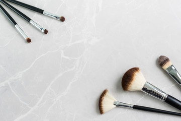 Set of six  black makeup brushes on a marble surface with copy space.