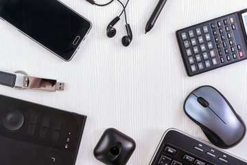 Top view on black modern office devices on a light background arranged in a circle with copy space in the middle.