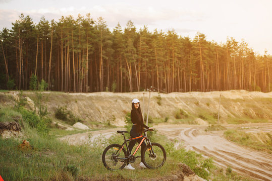 Bicyclist at the summer sunset on the desert road in the reserve territory. Full length image of female bicycle. Extreme mountain bike sport athlete woman riding outdoors lifestyle trail