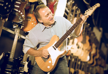 Happy man is playing on wooden electric guitar