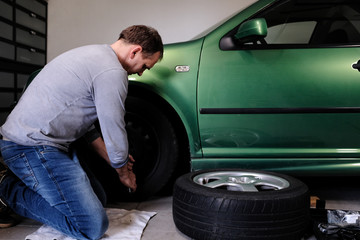 mann beim rad wechseln in der garage