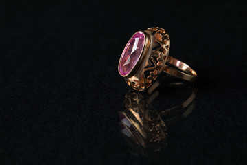 Golden ring with a ruby on a black background