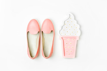 Flat lay of female fashion accessories, shoes and ice cream fairy lights on pastel color background. Beauty and fashion concept