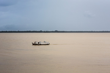 Typical boat sails on the river before a storm in the Amazon.