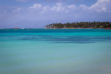 Turquoise and crystal clear sea in Guadeloupe, Sainte-Anne bay and beach. Windsurfers and kitesurfers enjoying the sport in background