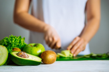 green fruits on front. woman cut fruits on background. healthy f