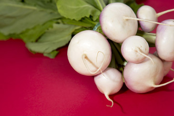 Close up shot of a bunch of turnips on a red background