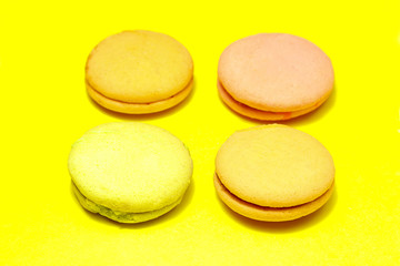 Delicious four multicolored macaroon on a yellow background
