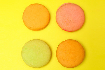 Obraz na płótnie Canvas Delicious four multicolored macaroon on a yellow background