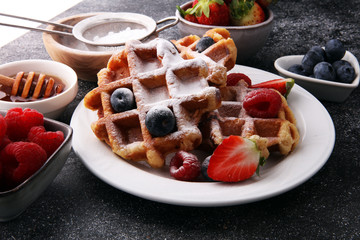 Traditional belgian waffles with fresh fruit and powder sugar on wooden board
