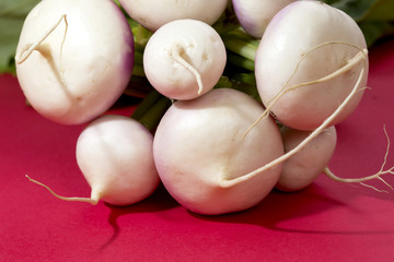 Close up shot of a bunch of turnips on a red background