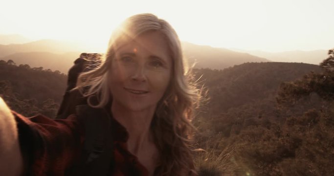 Senior woman hiker taking selfies standing on mountain edge