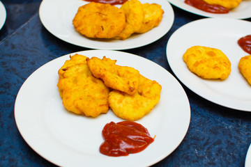 many servings of potato pancakes with ketchup on plates