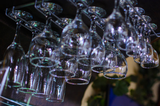 different cocktail glasses hanging over a bar rack