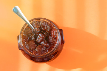 Jar of strawberry jam on orange background from top view