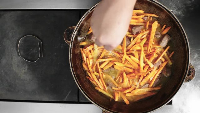 Close up shot of unrecognizable cook sprinkling dish with salt and cumin seeds when cooking pilaf, top view