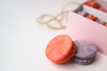 orange purple macaroons cakes next to the pink packaging with ropes