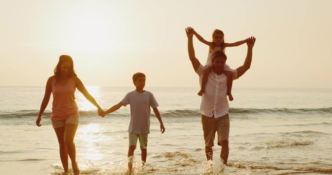 Happy young family on the beach at sunset