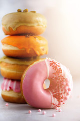 Stack of glazed colorful assorted donuts with sprinkles on grey cement background. Copy space. Sweet doughnuts for kids