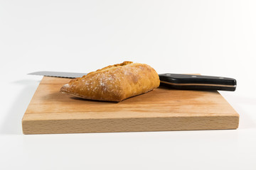 Wheat baguette and a bread knife on a wooden plate