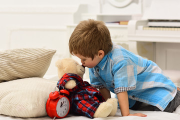 Child in bedroom kiss toy in nose. Good night concept. Boy with happy face puts favourite toy on...