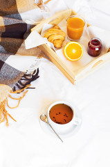Breakfast Bed Cup of tea Croissant Orange juice Fresh orange Jam Wooden tray Bed linen Plaid in a cage Morning breakfast at the hotel Interior concept Top view Copy Space