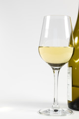 Ein Glas Weisswein und eine Flasche Wein auf weißem Hintergrund