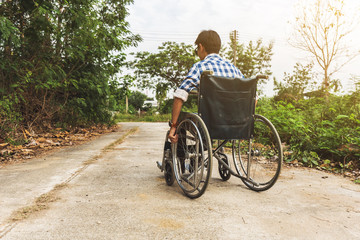 Young man sitting on wheelchair on the road.
