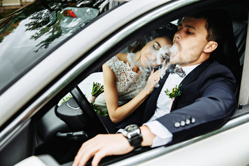 Wedding couple sitting and kissing in the car on their wedding day.