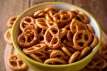 Mini pretzels with salt in a bowl on wooden background
