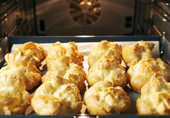 Homemade profiteroles in the oven. Process of baking cookies, French dessert, confectionery background. 
