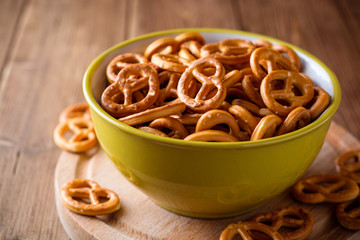 Mini pretzels with salt in a bowl on wooden background