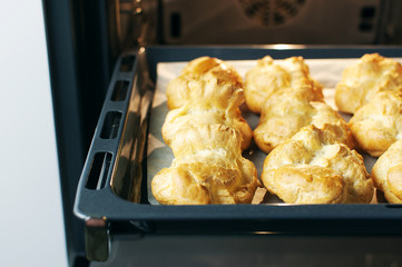 Homemade profiteroles in the oven. Process of baking cookies, French dessert, confectionery...