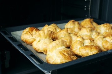 Homemade profiteroles in the oven. Process of baking cookies, French dessert, confectionery background. 