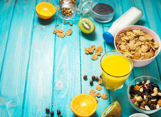 Healthy breakfast with bowl of cereal, orange juice, granola, milk, jam and fruits on blue wood background. Balanced diet.