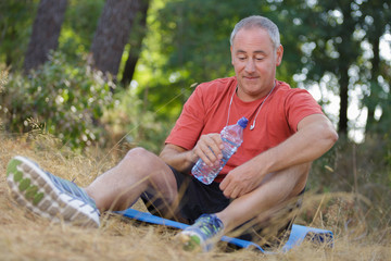 Naklejka na ściany i meble senior male jogger relaxing after exhausting training in the woods