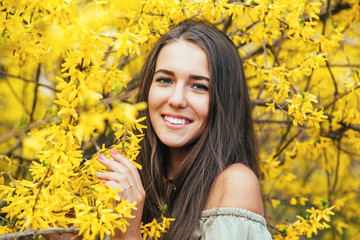 Happy smiling young woman with spring flowers at garden