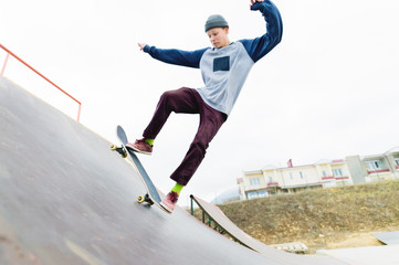 A skateboarder teenager in a hat does a trick with a jump on the ramp. A skateboarder is flying in the air