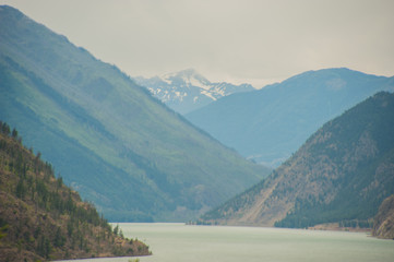 Canadas Westen, steile Bergh&auml;nge begrenzen die  Inside Passage, tr&uuml;be Regenstimmung, der Blick f&uuml;hrt den Fluss ins Bergpanorama.