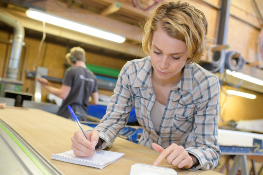 young woman construction worker writing on notebook