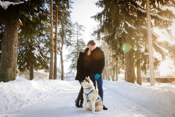 Fototapeta na wymiar young couple with a Siberian husky dog, winter forest sun