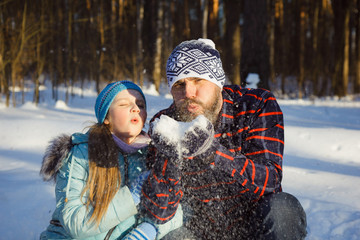 girl and man blowing on the snow