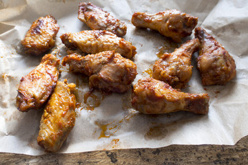 Appetizing fried pieces of chicken, pieces of chicken wings located on paper and on an old wooden background.